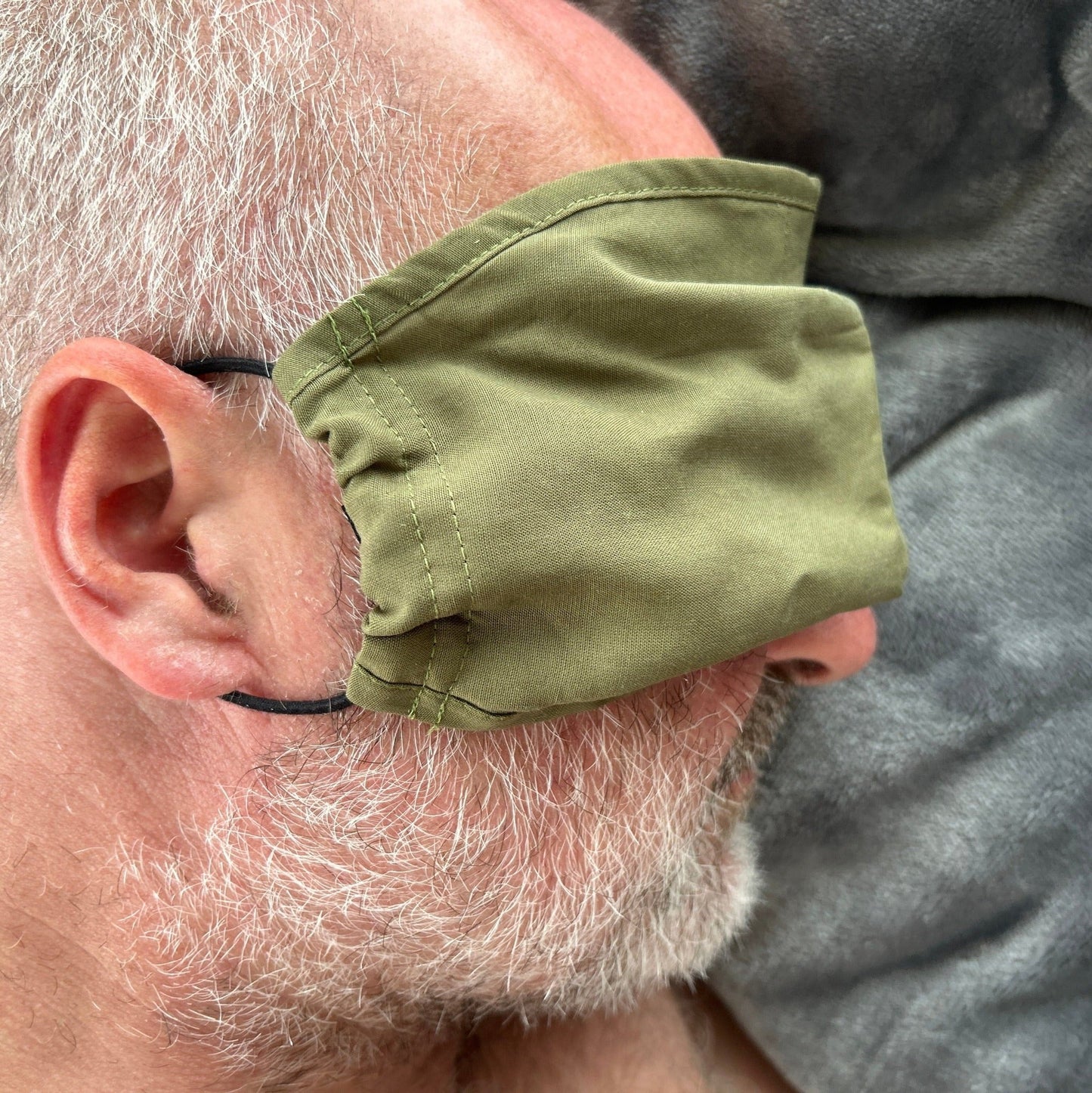 Mozzie Cozzie Mask, doubles as an eye/sleep mask on flights or when you need a quick snooze. One size, recycled elastics that are comfortable around the ears instead of at the back of the head.  Shown here in ActionMan Khaki/Olive and modeled by Jon.